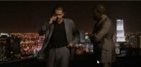 Crockett and Tubbs stand on a rooftop with the Miami skyline in the background as thunder claps in Miami Vice