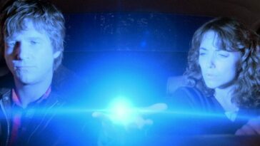 A man holds up a glowing ball in a car with a woman in Starman