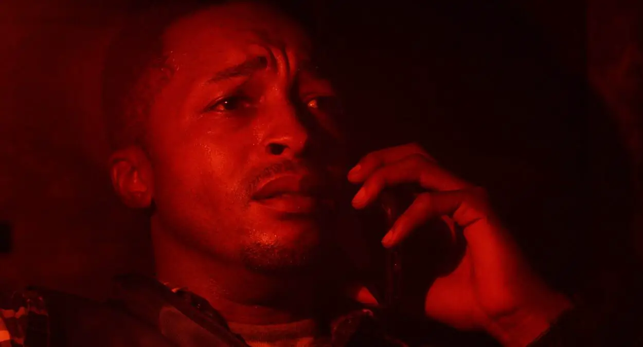 A frightened Sam (Hugh McCrae, Jr) makes a phone call, the image filtered in red.