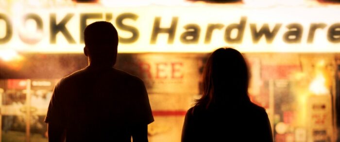 A silhouette of a man and woman in front of a hardware store.