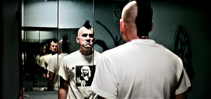 Michael Goorjian as Heroin Bob in SLC Punk!, his hair in a short black mohawk as he glares at his reflection in a mirror