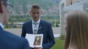 Dressed in suit and tie, Elder Tyler Davis shows Finnish people a bible in The Mission.