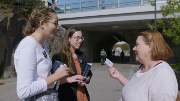 Sister McKenna Field and Carolina Debiassi speak to a skeptical Finnish citizen.