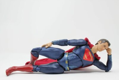 A Superman action figure poses laying on its side.