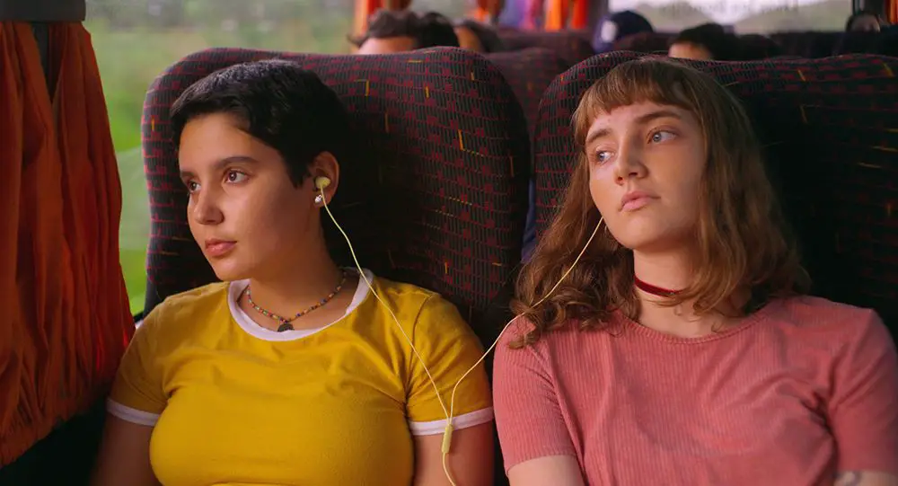 Sisters Luna and Marina, ride a bus and share headphones.