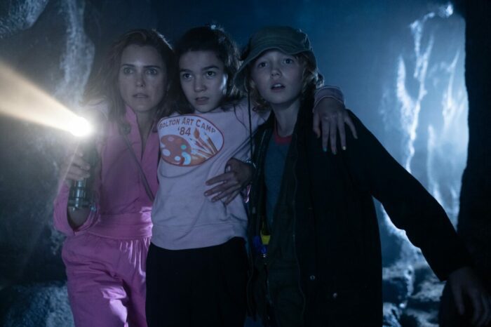 A mother with two pre-teens shines a flashlight in a cave in Cocaine Bear