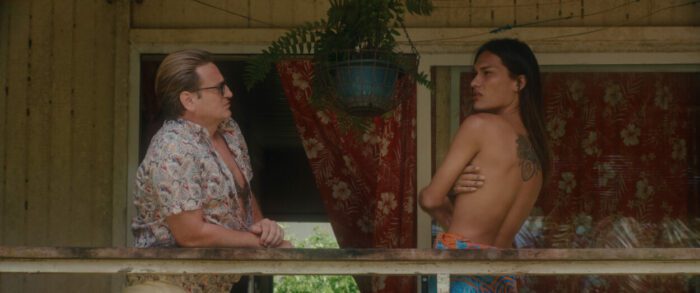 In Pacifiction, De Roller and Shanna face each other on a tropical balcony.