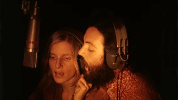 Paul and Linda McCartney sing into a recording studio microphone.