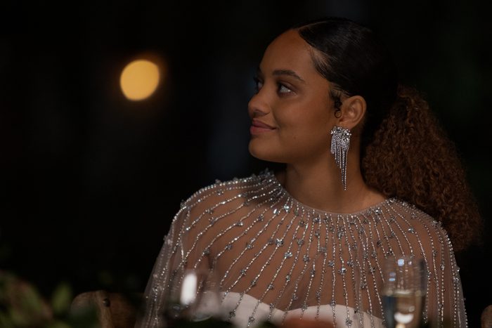 A woman in a glittery top looks over and smiles.