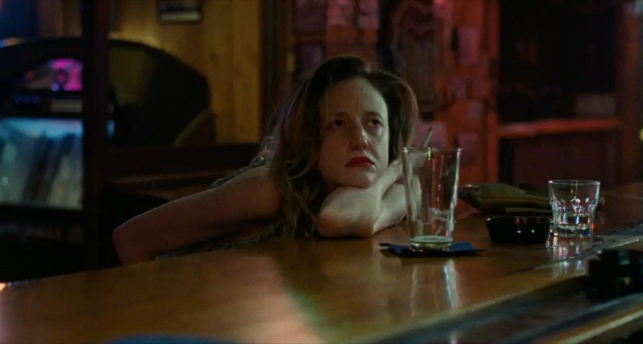 Andrea Riseborough as Leslie drinks at a bar.