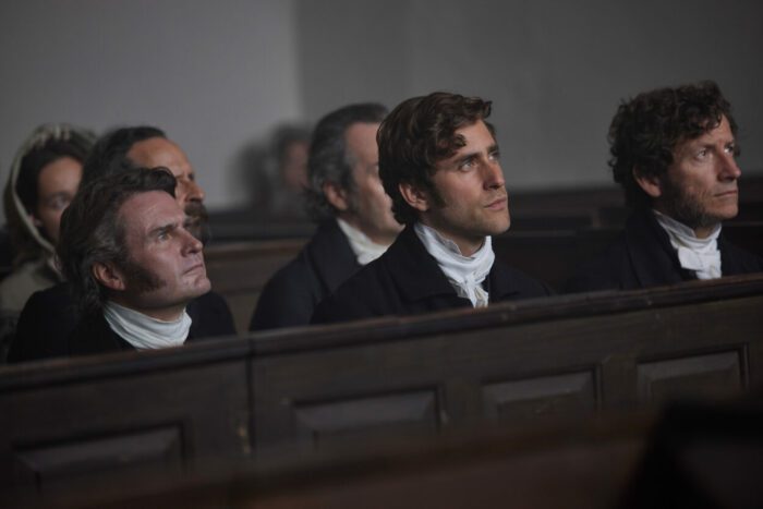 Men are looking towards the speaker in a church.