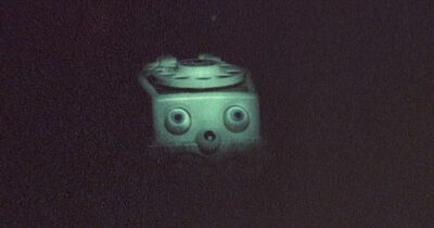 A grainy scene of an old telephone with eyes from Skinamarink. 