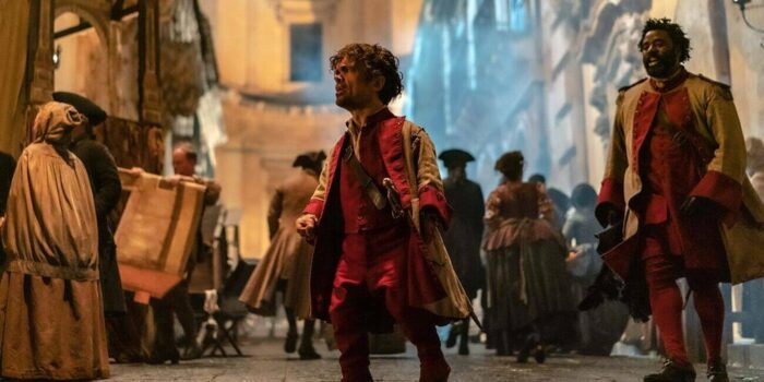A shot of Peter Dinklage with clenched fist in a public square taken from Joe Wright's 2021 musical Cyrano.