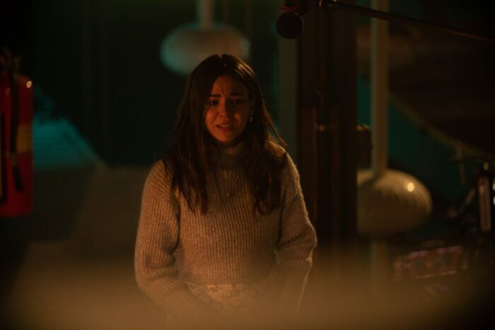 Annie (Victoria Justice) stands in a dark room, looking distraught.