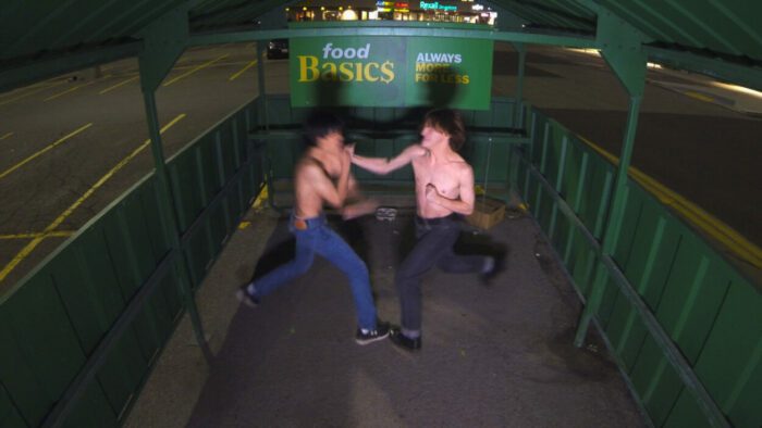 Two boys shirtless having a bareknuckle fistfight in a grocery cart shelter