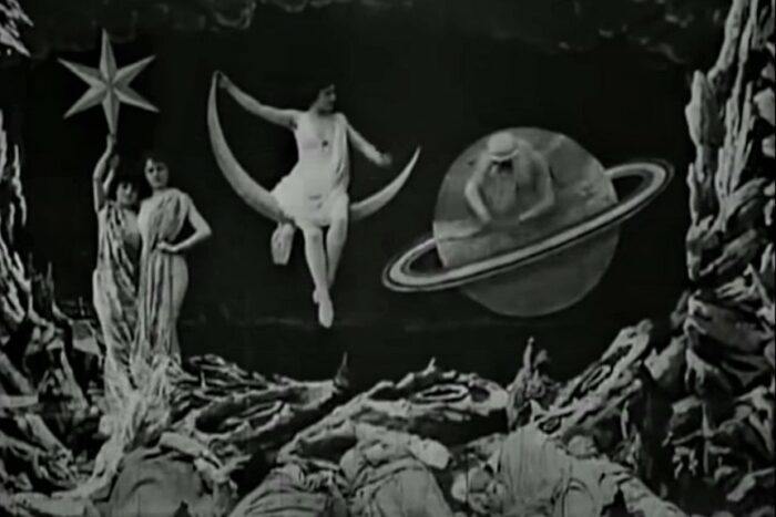 Fantastical scene of women riding crescent moons and holding up stars set against the landscape of the moon in the Georges Méliès silent film A Trip to the Moon (1902)