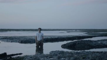 A man stands knee deep in a marsh in Infinite Sea