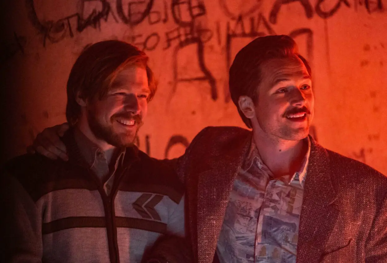 Two men smile at an underground night club in Tetris.
