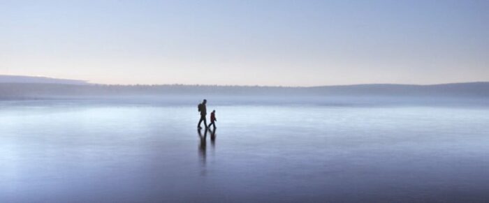 A man and a child walking on a frozen lake