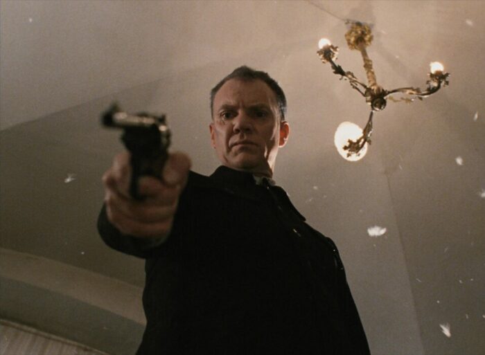 Malcolm McDowell as Yanovsky, firing a gun at the unseen Tsar.