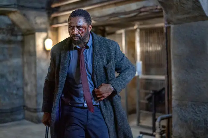 A bloodied Idris Elba as John Luther clutches his coat in Luther.