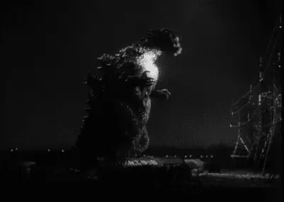 Godzilla in "Godzilla" approaching powerlines with a spotlight shining onto its chest