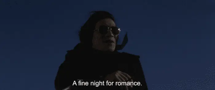 A man in "Godzilla vs Mechagodzilla" clad in a black coat and sunglasses saying the line "A fine night for romance"