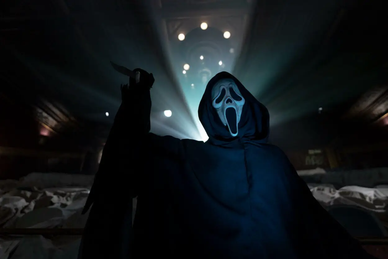 Ghostface raises their knife with lights illuminating them in the background.