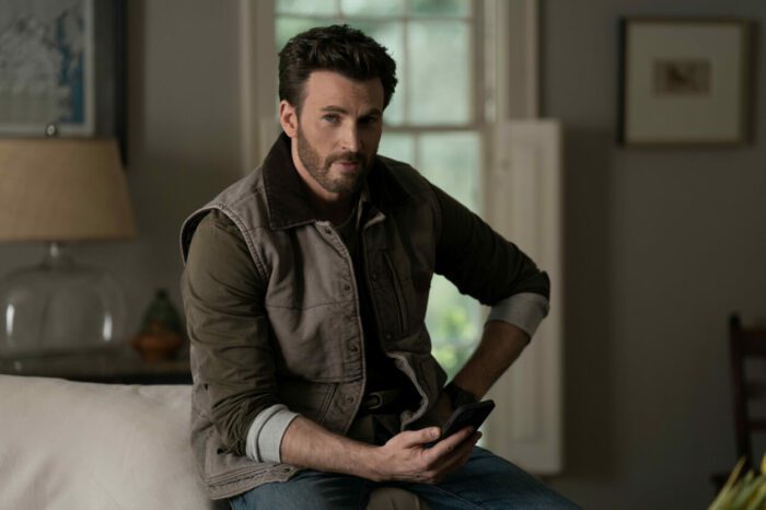 Chris Evans in Ghosted, sitting in his farm house with his phone in hand