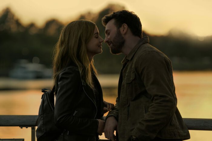Ana de Armas and Chris Evans in Ghosted on a bridge leaning into a kiss at dawn