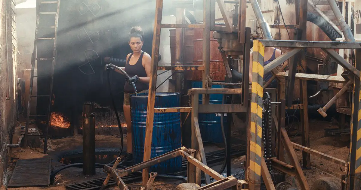 Women work in a makeshift factory surrounded by barrels of gasoline.