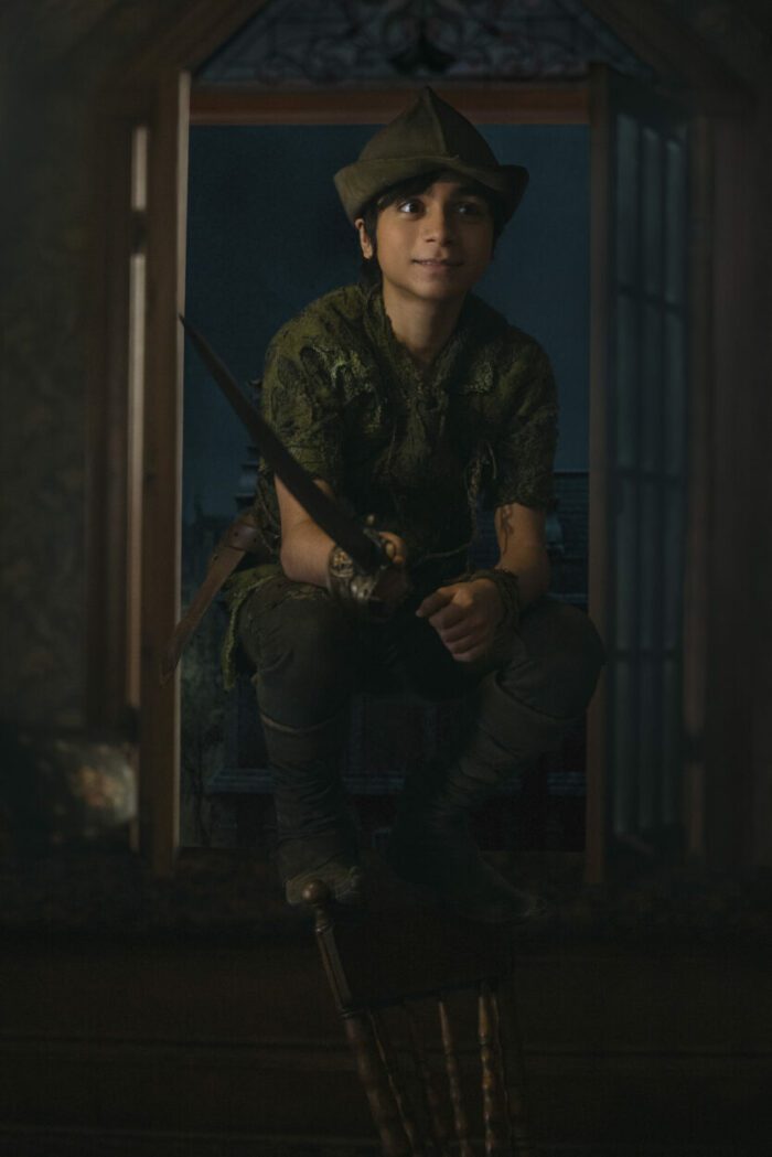 Peter Pan stands at a window with a sword.