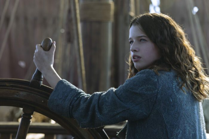A girl sets her hands to steer a ship.