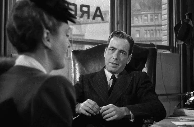 Sam Spade sits at his desk and listens to a new client tell her story.