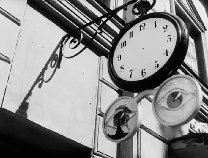 A street clock without hands and the glasses below it with drawing of eyes inside its frame