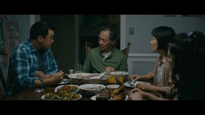 The Moua family is having dinner together at the table.