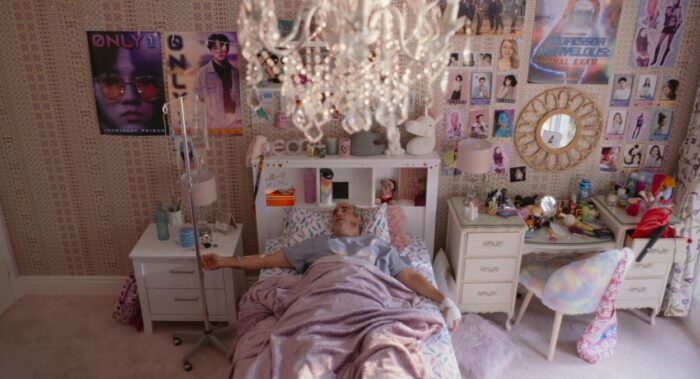 Beau lays in the bed of a teenage girl, the walls covered in Kpop posters