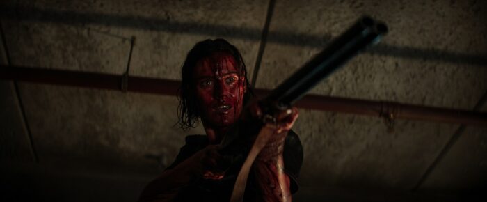 Beth (Lily Sullivan) covered in blood, wielding a shotgun