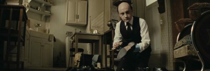 A film still from film Monsieur Hire, showing the titular character shining shoes.
