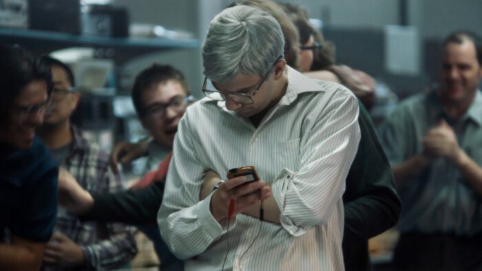 Mike is hunched over, looking intently at a BlackBerry prototype