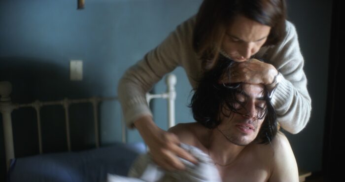 A woman tends to the wounds of an injured man.