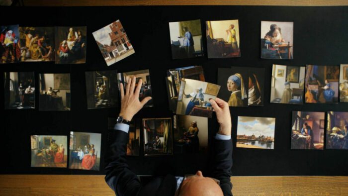 Overhead shot of a woman arraning a series of images of Vermeer's paintings