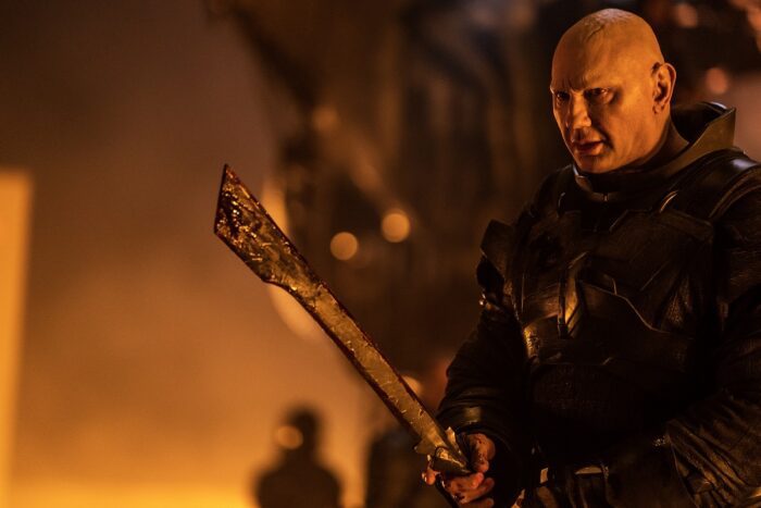 Dave Bautista as Rabban in Dune: Part Two, weilding a weapon and girded for battle.