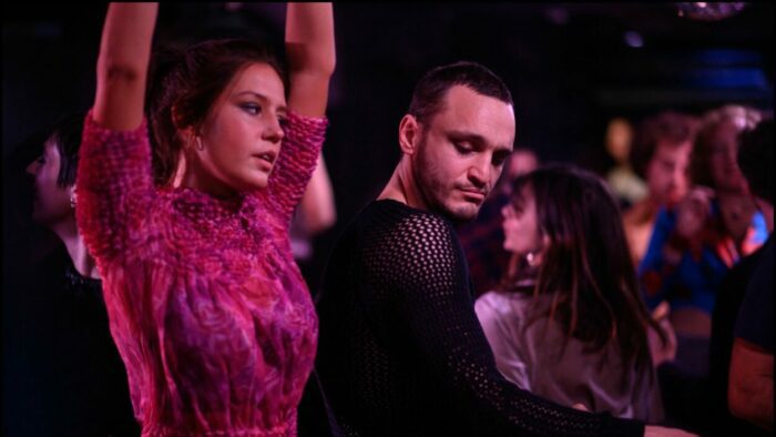 A woman dances at a club as a man turns to watch.