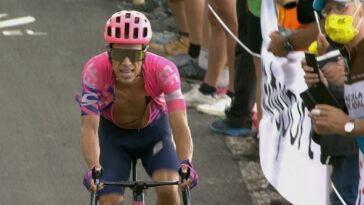 An open-shirted cyclist nears a stage finish line at the Tour de France.