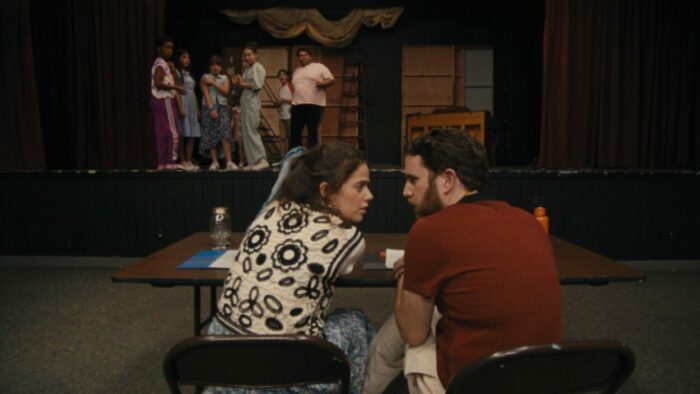 a man and woman confer at the director's table of a small theatrical production.
