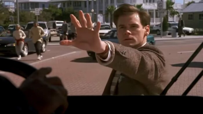 Truman puts his hand out to stop a bus in The Truman Show