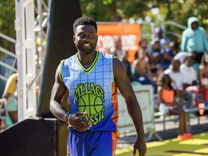 A man smiles in a colorful basketball uniform
