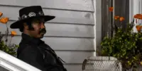 Johnny Black sitting on the front porch of a white house