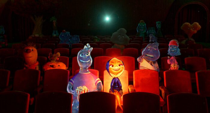 Wade and Ember, who is wearing a hood and illuminating the theater, watching a movie with other elements in the background.